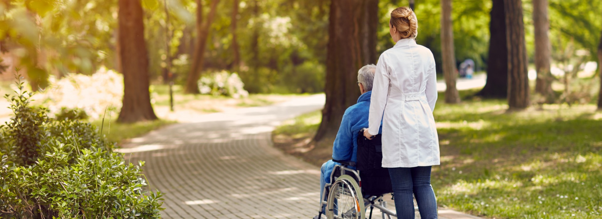 Nurse pushing elderly patient in wheel chair Gracia Hospice